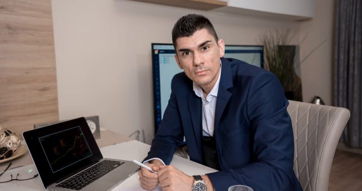 Businessman in blue suit working on laptop in sleek office setting, conveying professionalism and focus.