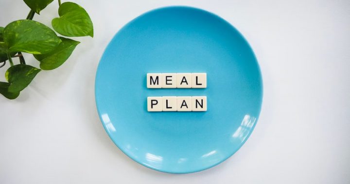 Innovative meal planning concept using alphabet tiles on a blue plate with green leaves.